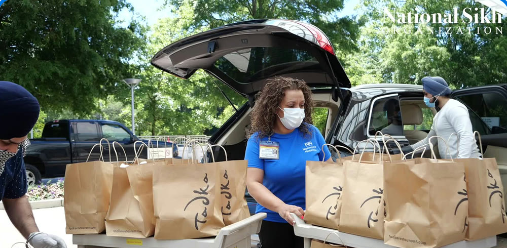 NSO volunteers loading bags of prepared meals into a car outside Gwinnett Medical Center